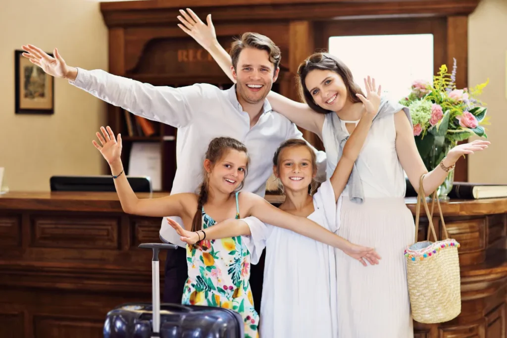 Família sorrindo durante check-in em hotel com crianças e malas em ambiente acolhedor de Florianópolis