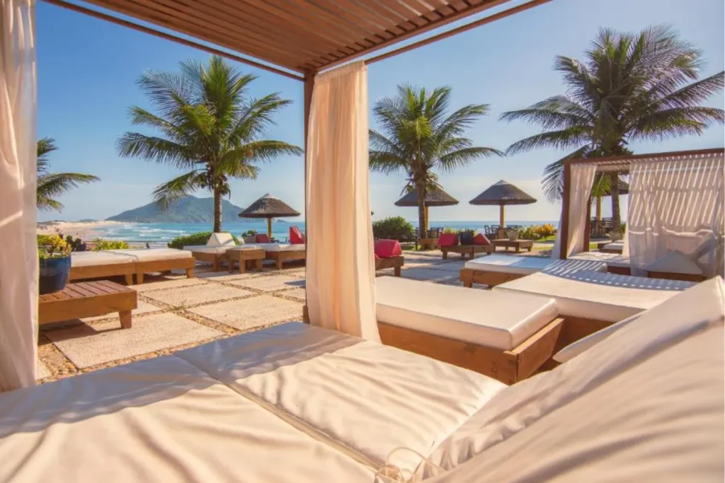 Espreguiçadeiras e cabanas próximas à praia no Costão do Santinho durante dia ensolarado em Florianópolis.