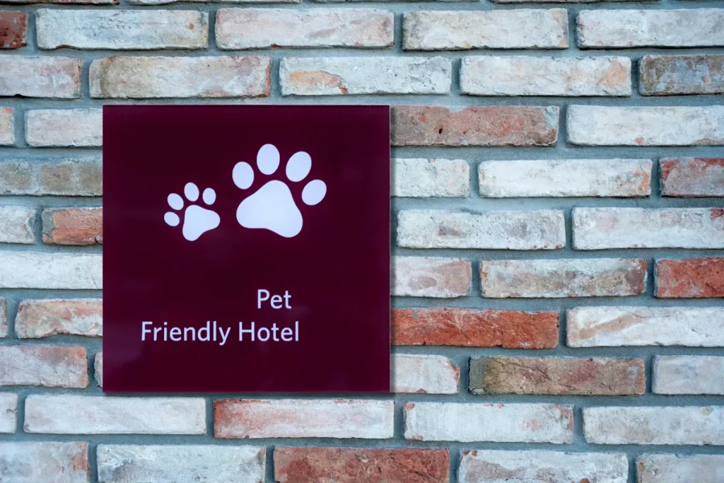 Placa de hotel pet friendly com símbolo de patas instalada em parede de tijolos em hospedagem de Florianópolis