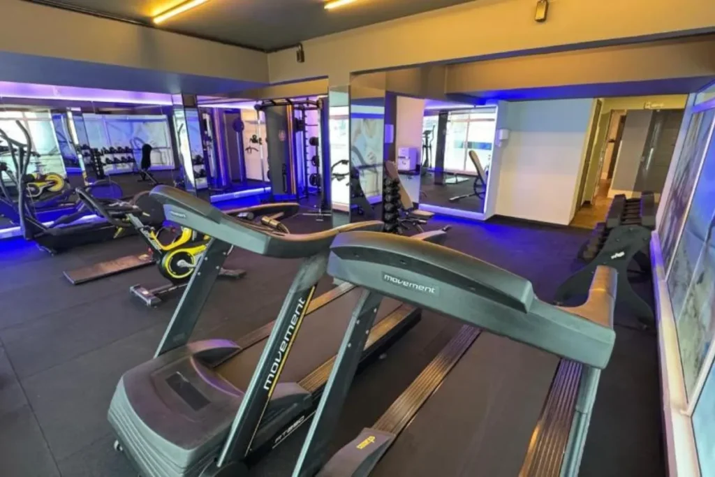 Academia de hotel equipada com esteiras, pesos e aparelhos de musculação em ambiente moderno