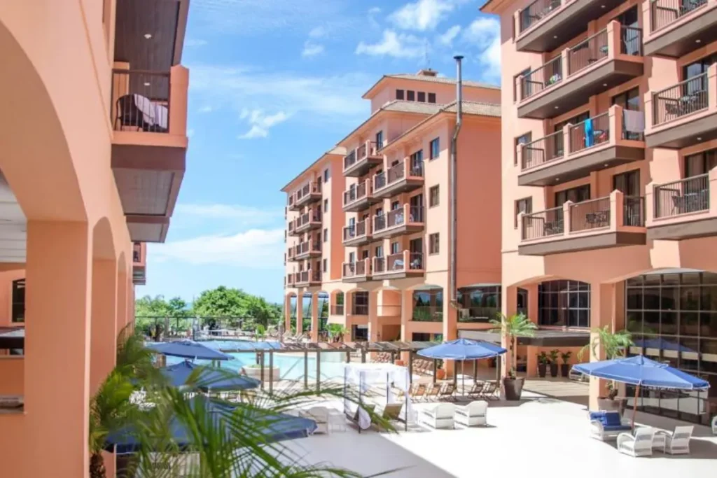 Corredor externo do Jurerê Beach Village com piscina, espreguiçadeiras e apartamentos próximos à praia.
