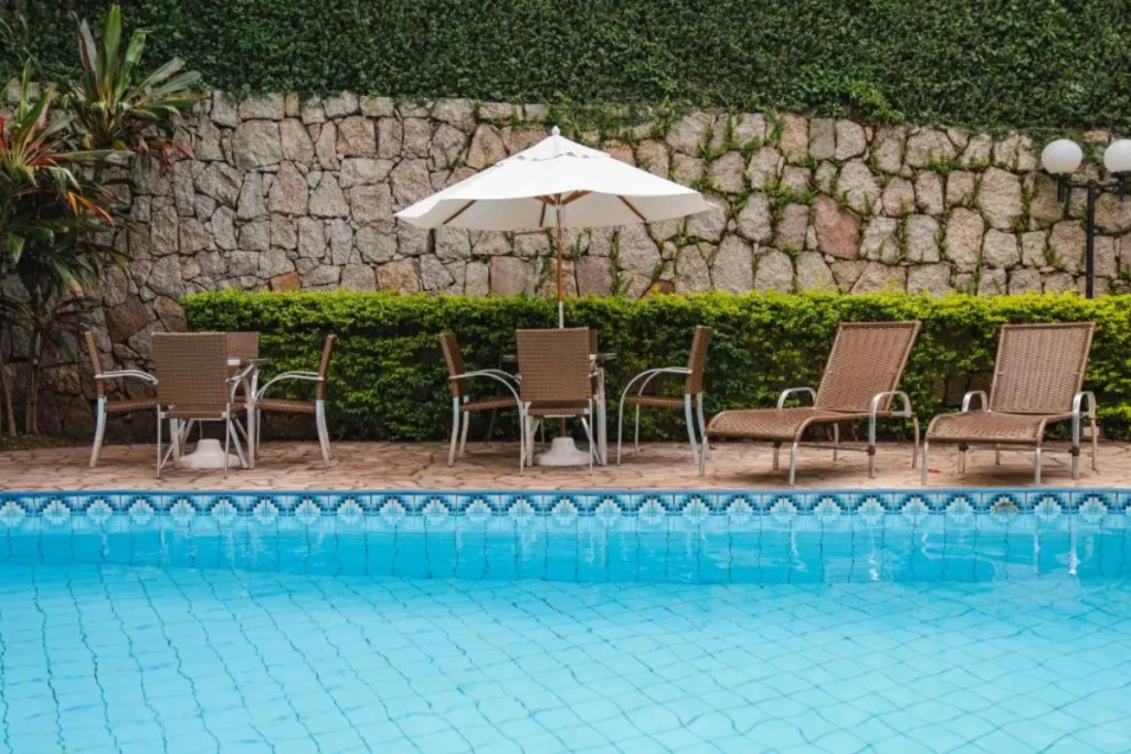 Área da piscina externa do Hotel Slaviero Baía Norte com espreguiçadeiras e jardim em Florianópolis