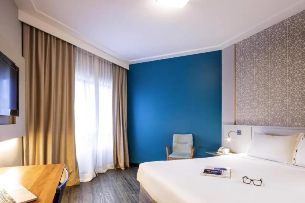 Quarto do Hotel Mercure Florianópolis com cama confortável, decoração moderna e iluminação suave