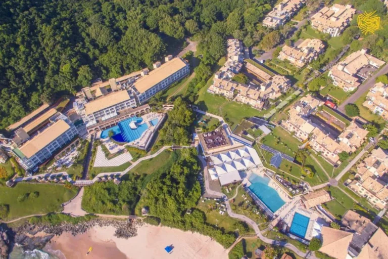 Vista aérea do Costão do Santinho com praia, piscinas e grande estrutura turística em Florianópolis.