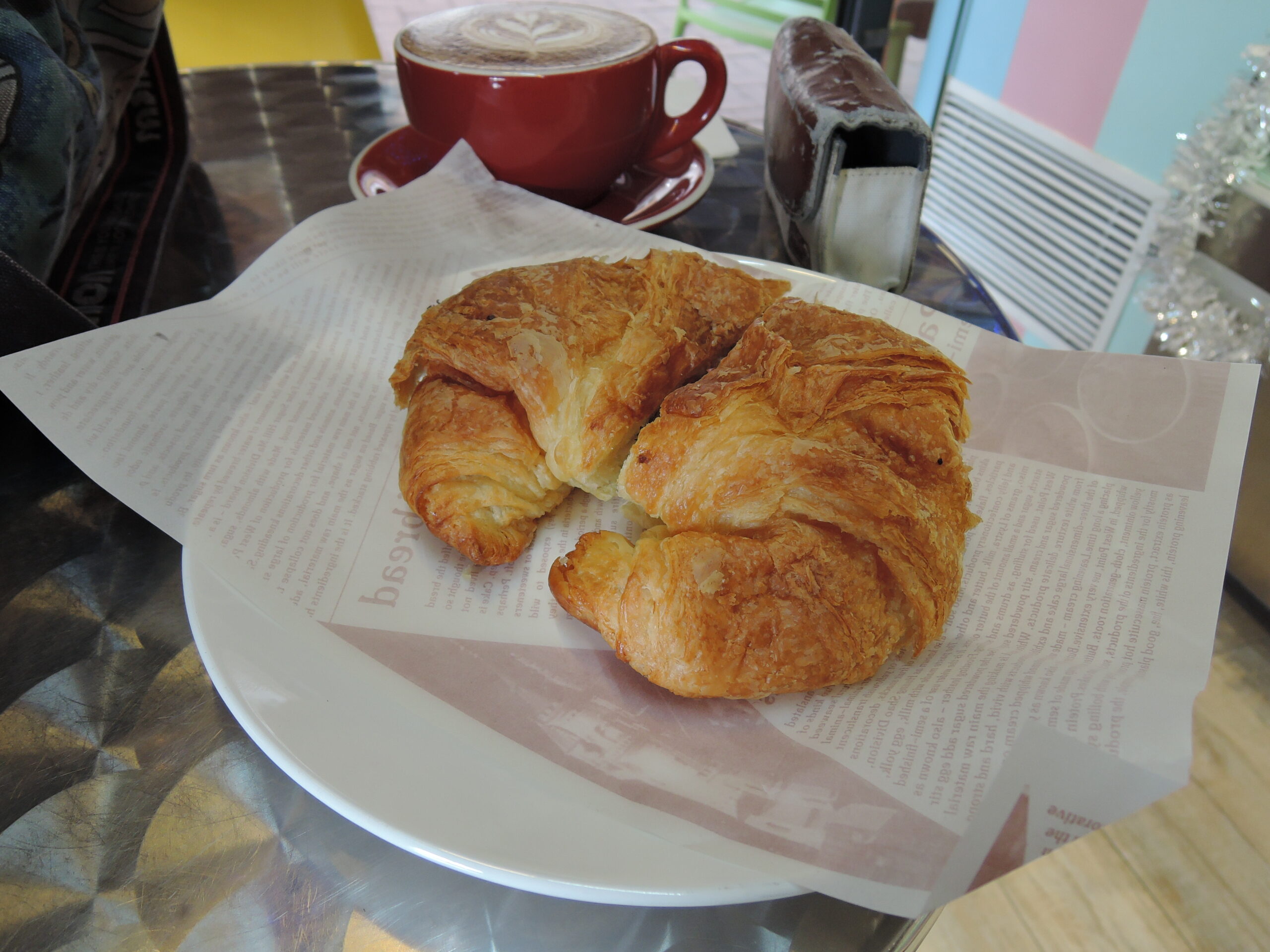 Croissants servidos em prato com uma xícara de café ao fundo.