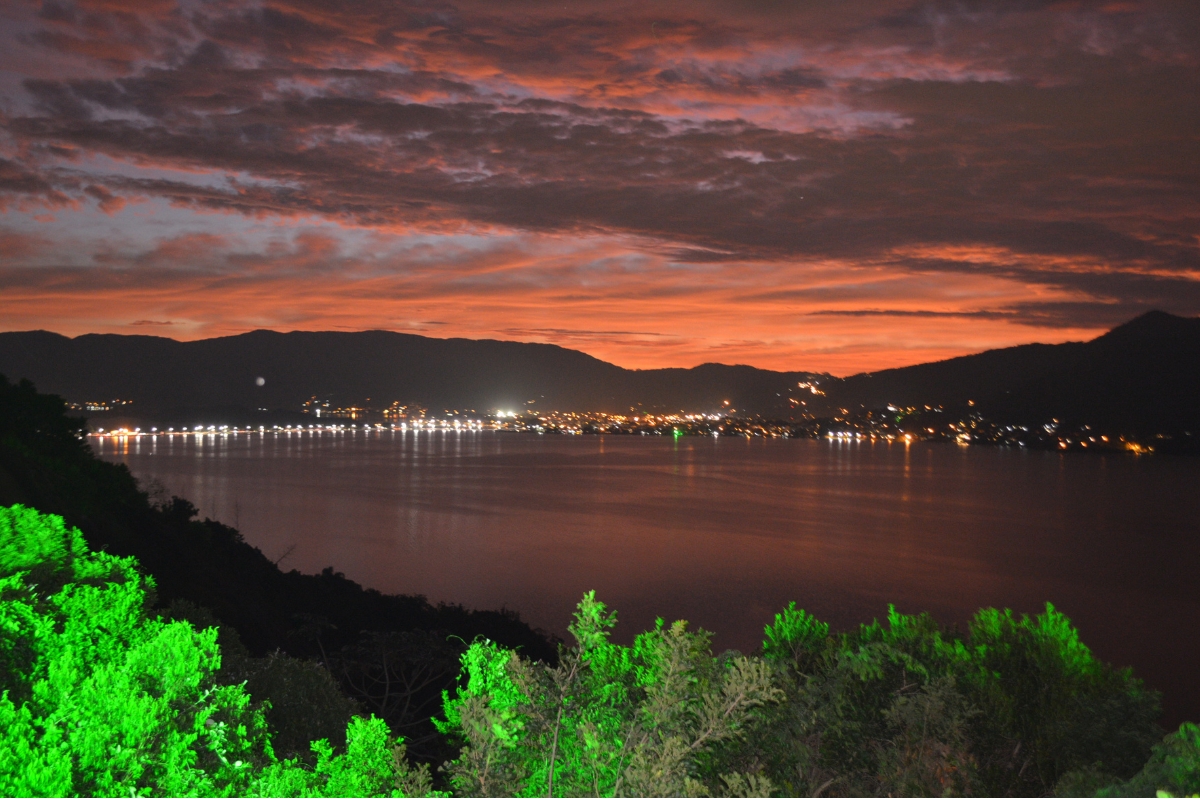 Vista noturna da Lagoa da Conceição com luzes urbanas refletidas na água