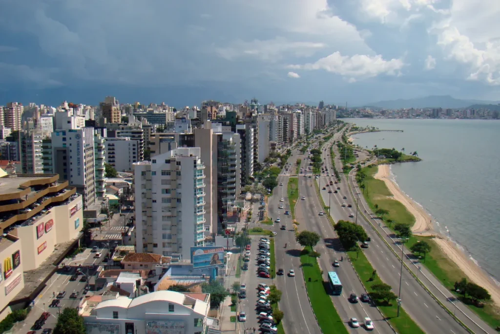 Vista panorâmica da Avenida Beira-Mar Norte em Florianópolis, com prédios, trânsito e a baía.