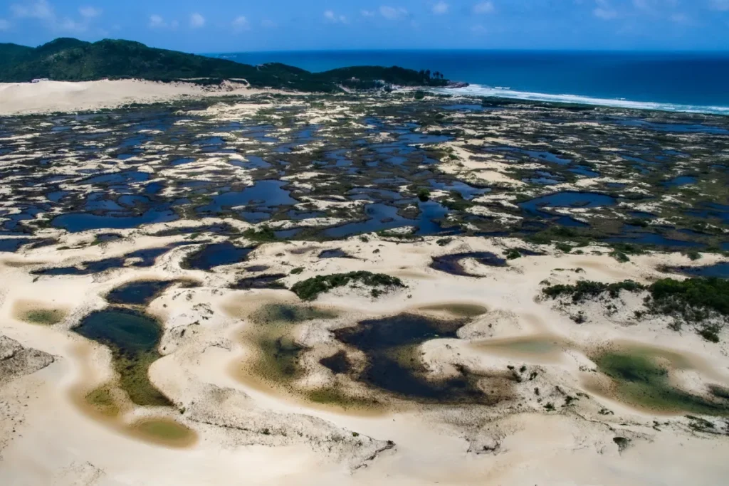 Vista aérea de dunas, vegetação e pequenas áreas alagadas próximas à Lagoa da Conceição, em Florianópolis.