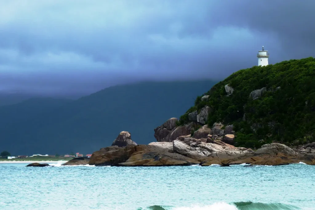 Farol de Naufragados sobre costão rochoso e vegetação na Praia de Naufragados, em Florianópolis.