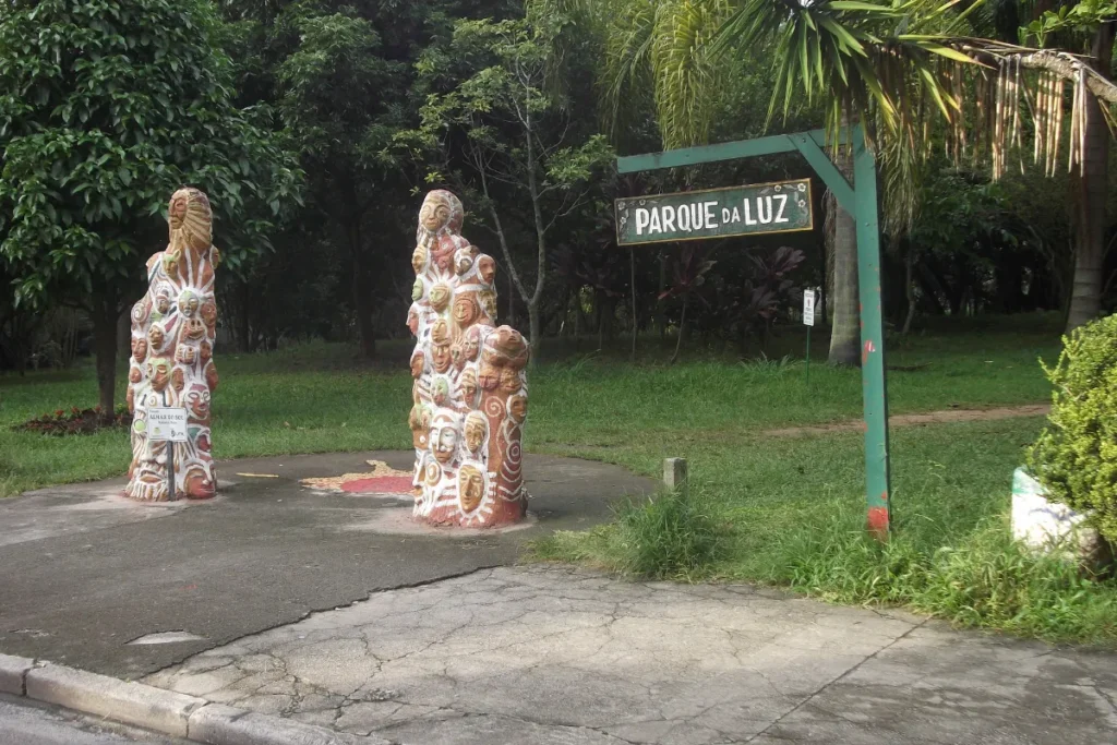 Entrada do Parque da Luz, em Florianópolis, com placa de identificação, esculturas e área arborizada.