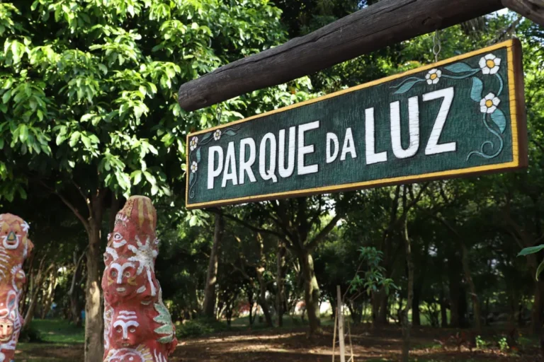 Placa do Parque da Luz em Florianópolis, cercada por árvores e esculturas decorativas.