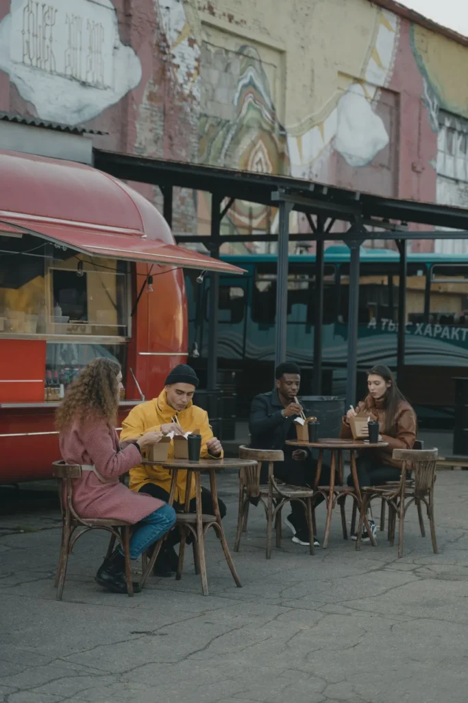 Pessoas sentadas para comer ao ar livre junto a um food truck