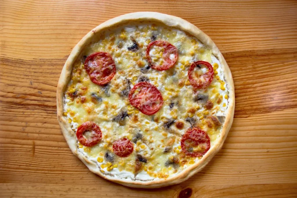 Pizza com queijo, tomate e outros ingredientes sobre uma mesa