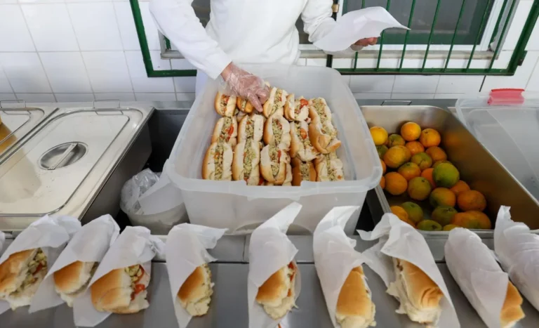 Merendeira organiza lanches embalados e caixa de laranjas na cozinha de uma escola estadual de Santa Catarina